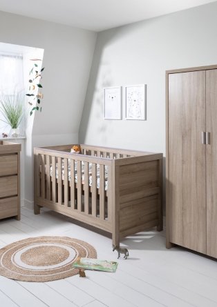 Nursery with dark brown cot and cupboard and rattan mat.
