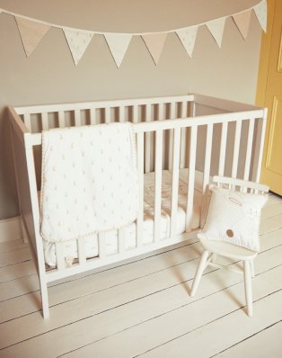 Nursery with cot, flags garland and wooden chair.