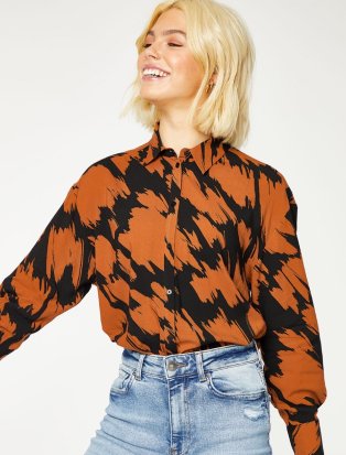 Woman wearing black and orange patterned shirt with jeans.