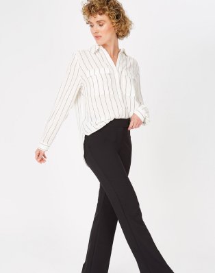 Woman wearing black trousers and white button up shirt.